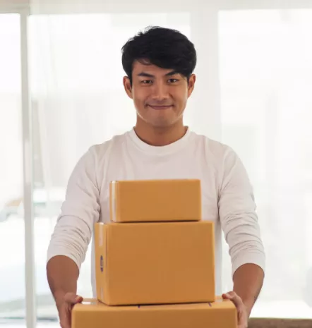 Man smiling and holding cardboard boxes